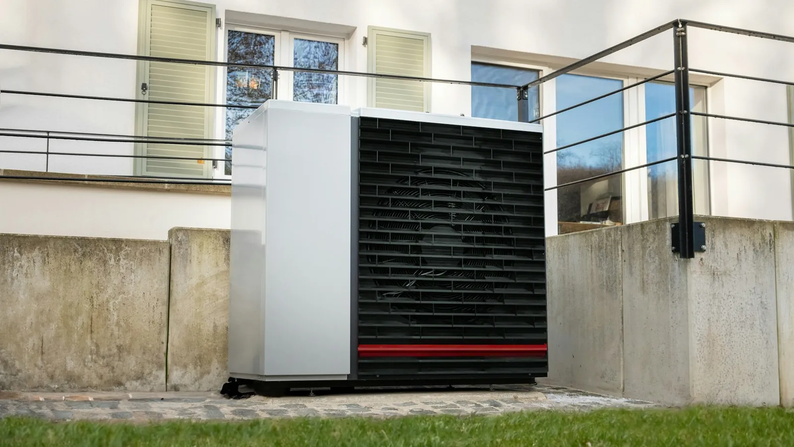 Wärmepumpe auf einer Terrasse vor einem Wohnhaus